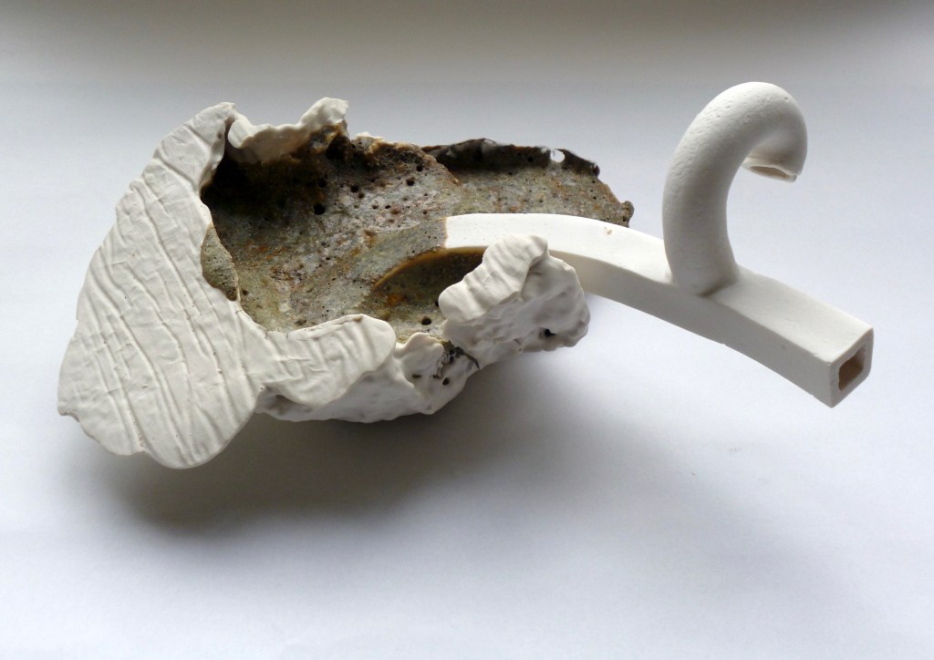 Porcelain paper slumped over a box, oozing melted brick with rod like structure emerging from the brick.